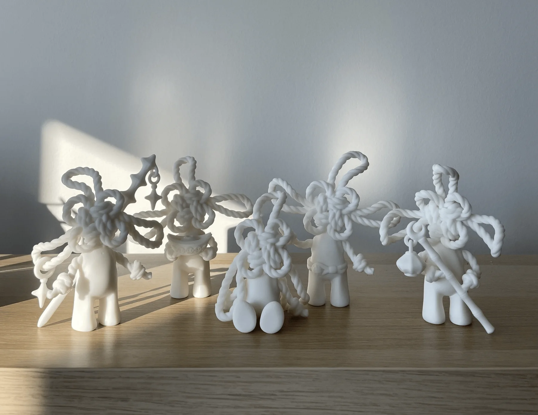 Five resin printed FUSHI figurine variations lined up on a wooden table